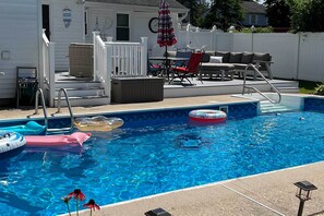 A swimming pool with inflatable toys, a covered seating area, and a white fence. - Inviting Home w/ Inground Pool: 3 Mi to Beach (Brick)