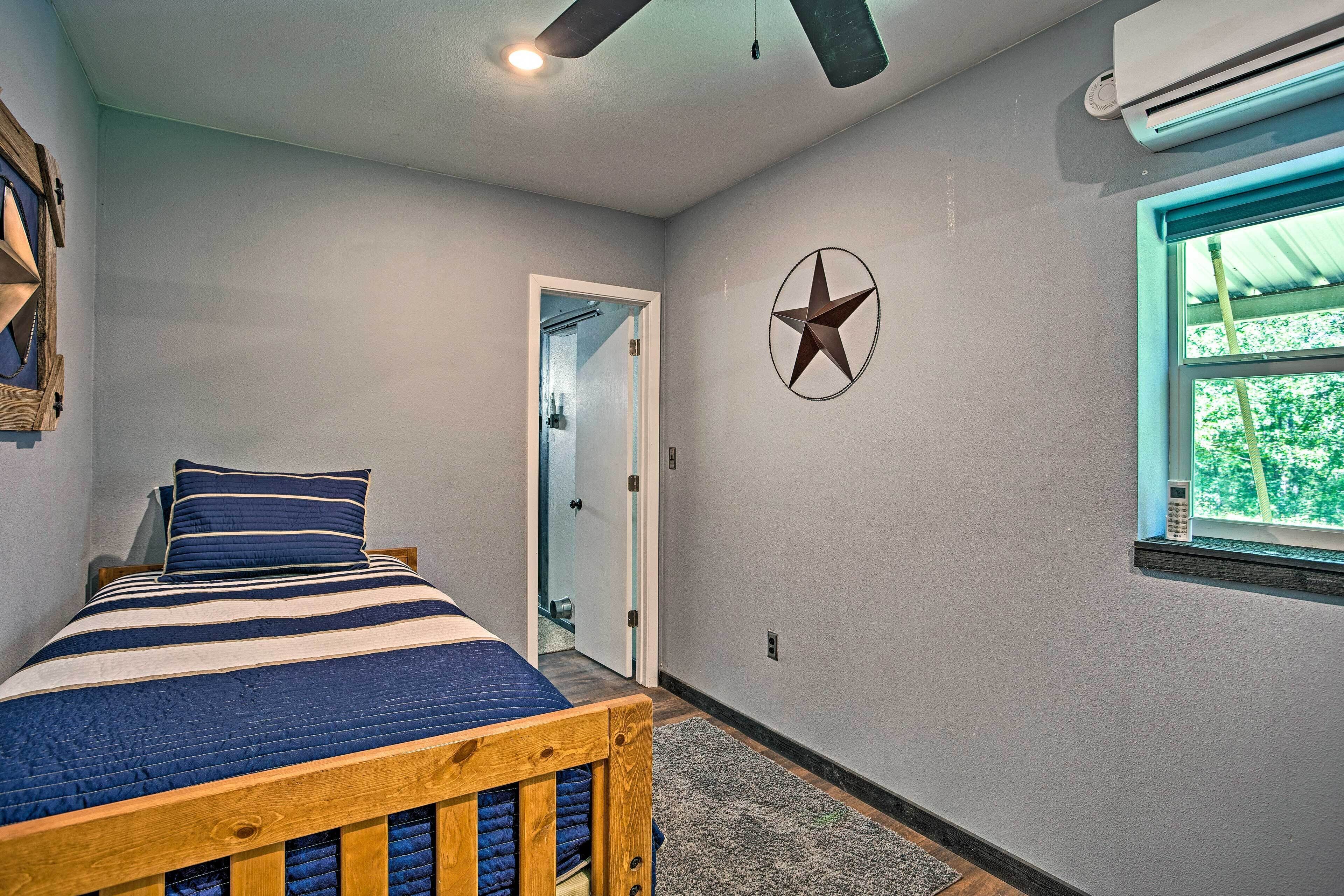 A bedroom with a bed, a ceiling fan, a window with a view, and a star decoration on the wall.
