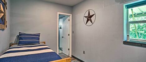 A bedroom with a bed, a ceiling fan, a window with a view, and a star decoration on the wall.