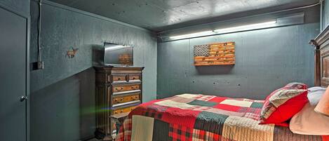 A bedroom with a bed, dresser, and a television on a stand.