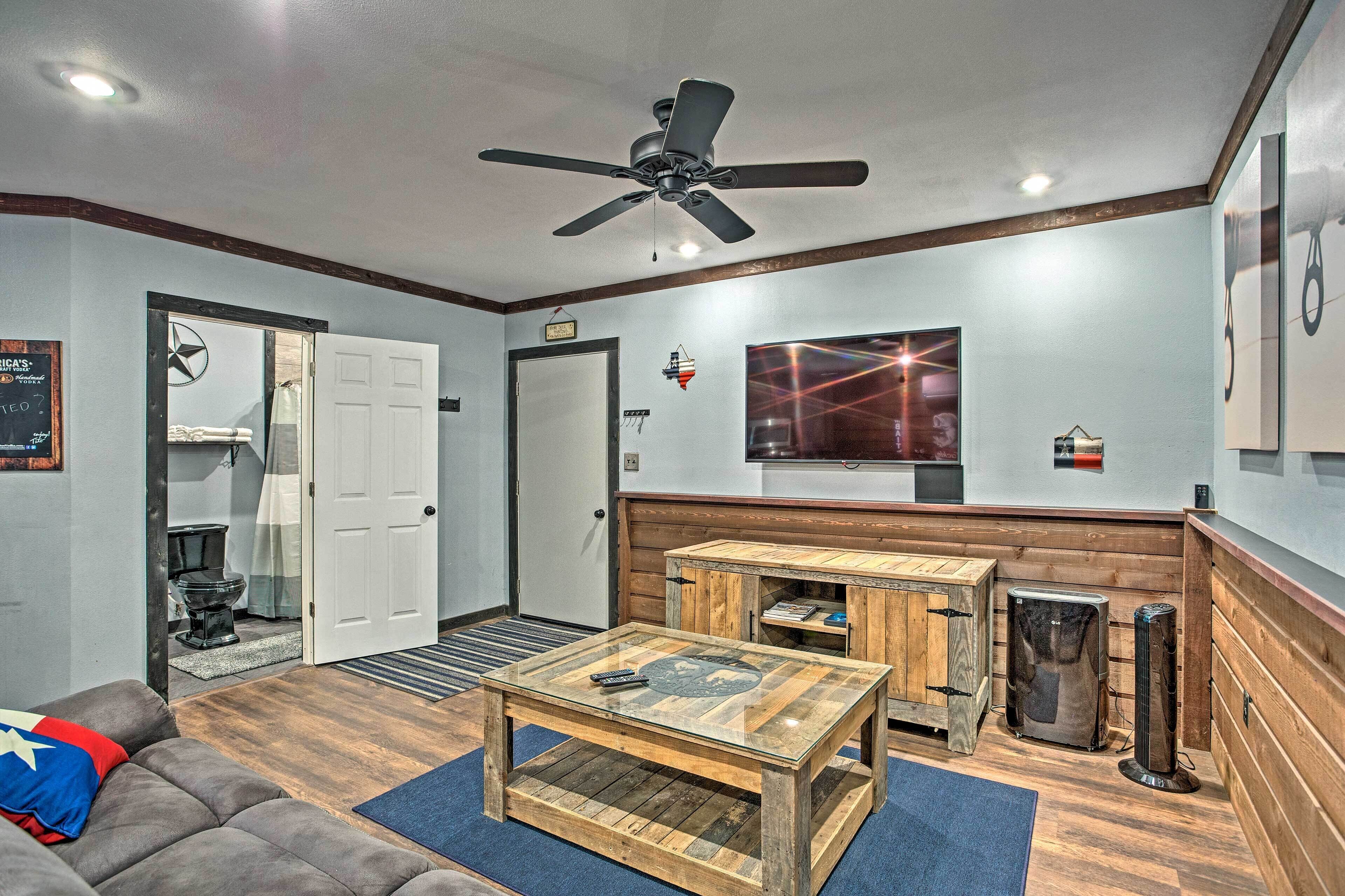 A living room with a ceiling fan, a wooden coffee table, a sofa, and a television on the wall.