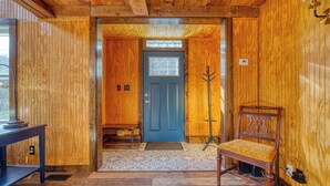 Interior de madeira com uma porta azul, um banco e uma mesa.