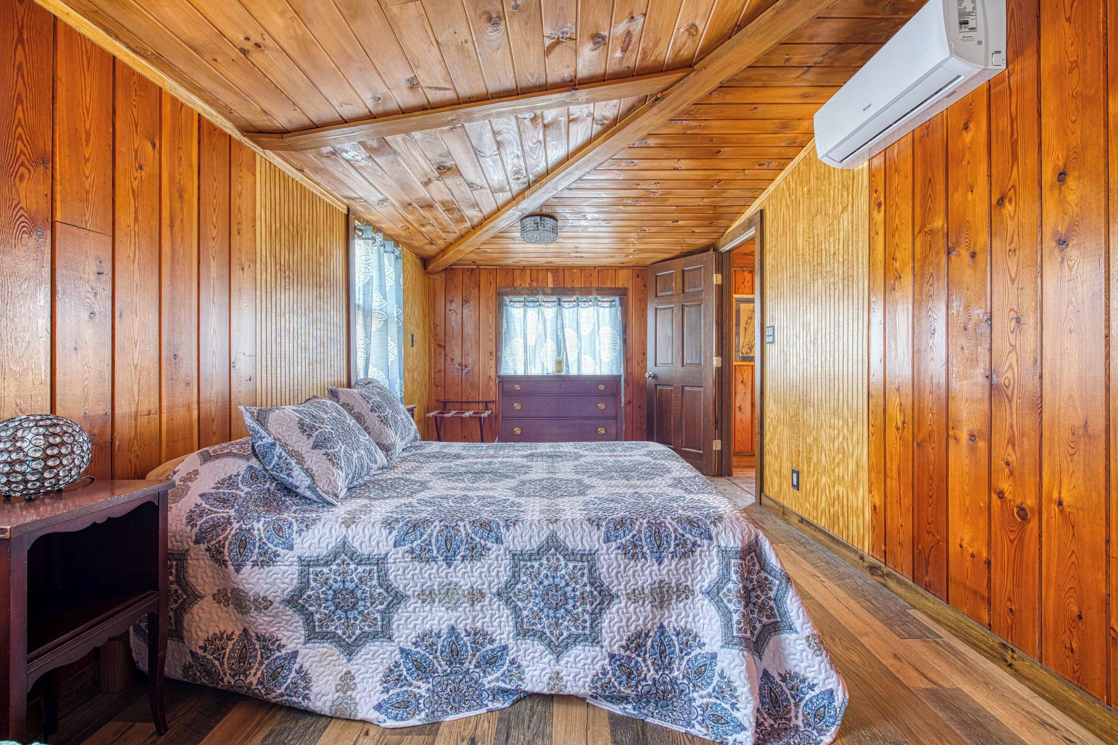 Quarto de cabana de madeira com cama, cômoda e ar condicionado.