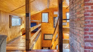 Interior em madeira com escada, paredes de madeira e um pilar de tijolos.