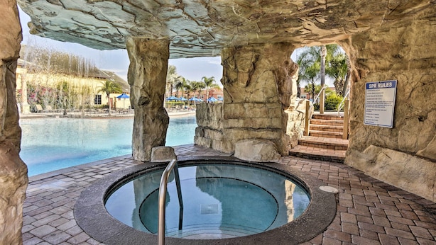 A stone-enclosed hot tub area with a pool in the background. - Grou-friendly Kissimmee Home: 7 Mi to Disney Parks (Kissimmee)