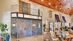 A lobby with a wooden ceiling, a balcony with a sign reading "Paradise Palms Cinema," and a seating area with various chairs and tables. - Grou-friendly Kissimmee Home: 7 Mi to Disney Parks (Kissimmee)