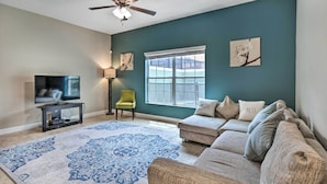 A living room with a large window, a ceiling fan, a television on a stand, and a patterned rug. - Grou-friendly Kissimmee Home: 7 Mi to Disney Parks (Kissimmee)