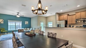 A spacious dining area with a dark wooden table and patterned chairs, a ceiling fan, and a chandelier. - Grou-friendly Kissimmee Home: 7 Mi to Disney Parks (Kissimmee)