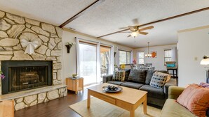 A living room with a stone fireplace, a wooden coffee table, a sofa, and a ceiling fan.
