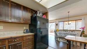 A kitchen with wooden cabinets, a black refrigerator, and a dining area with a table and chairs.