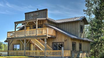 A two-story wooden building with a balcony, a staircase, and a metal roof.