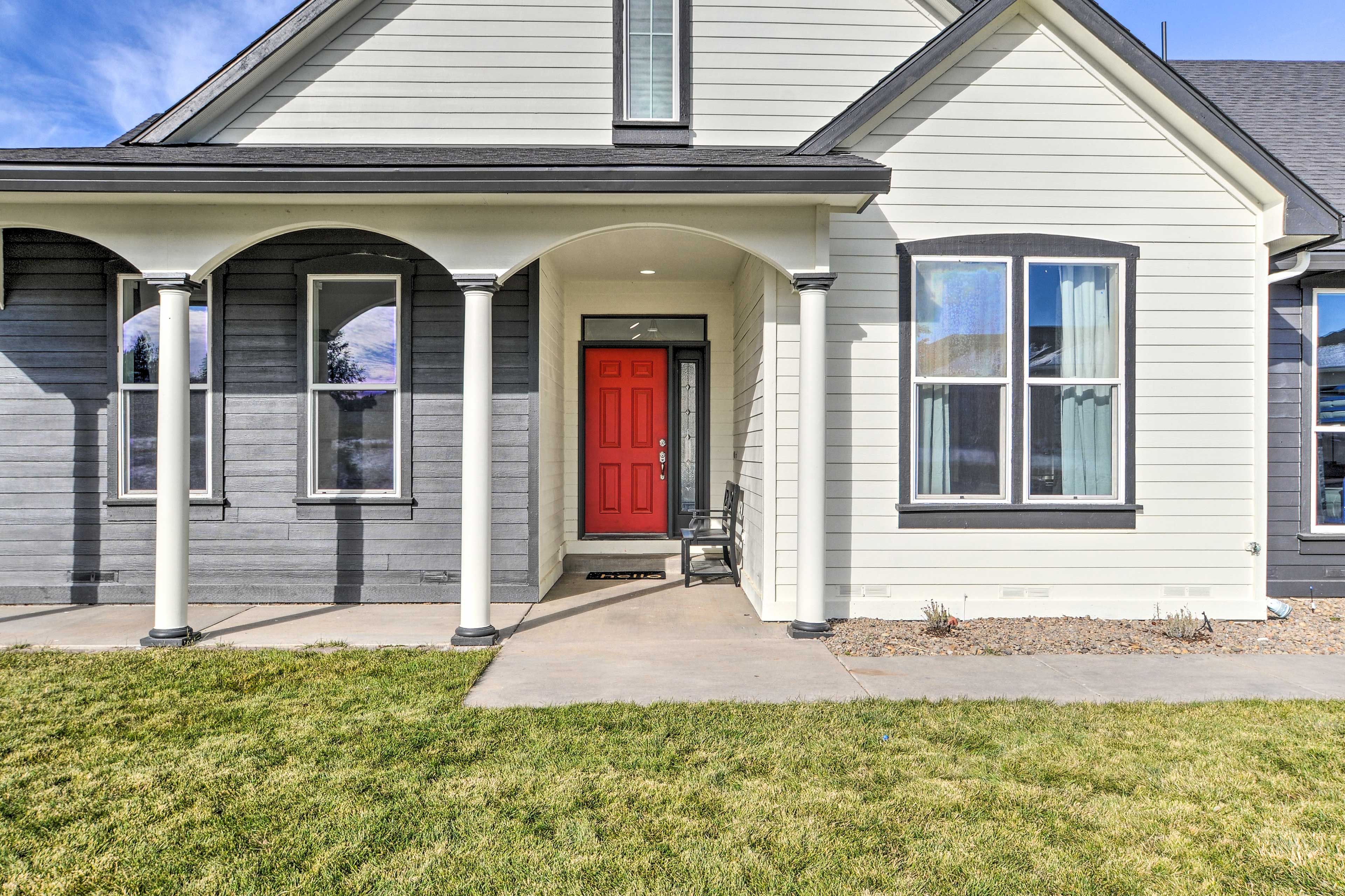 A two-story house with a red front door, white siding, and a covered front porch with columns.