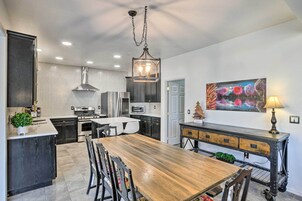A modern kitchen with a wooden dining table, dark cabinetry, and a hexagonal tile backsplash.