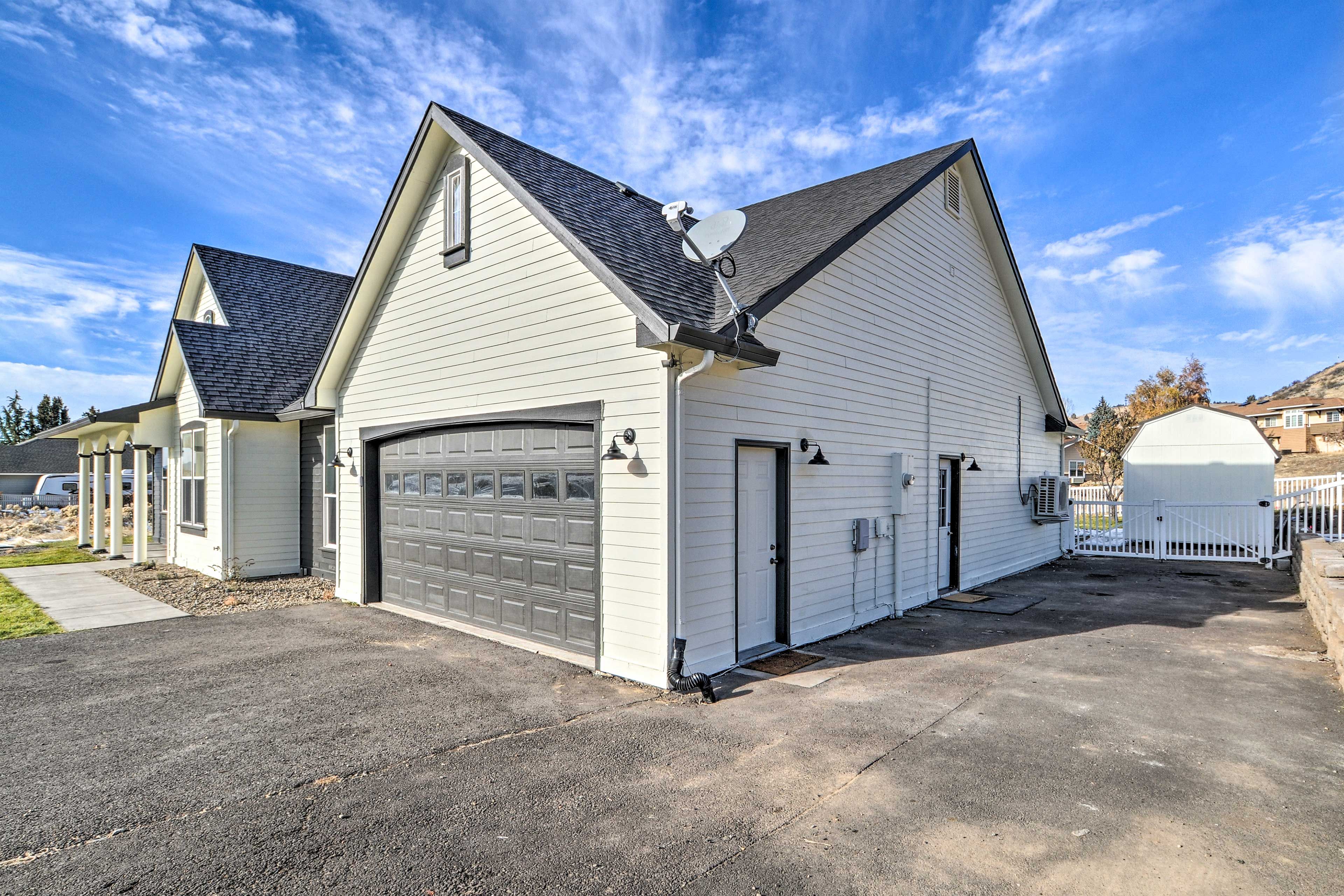 A two-story residential building with a garage, satellite dish, and a fenced yard.