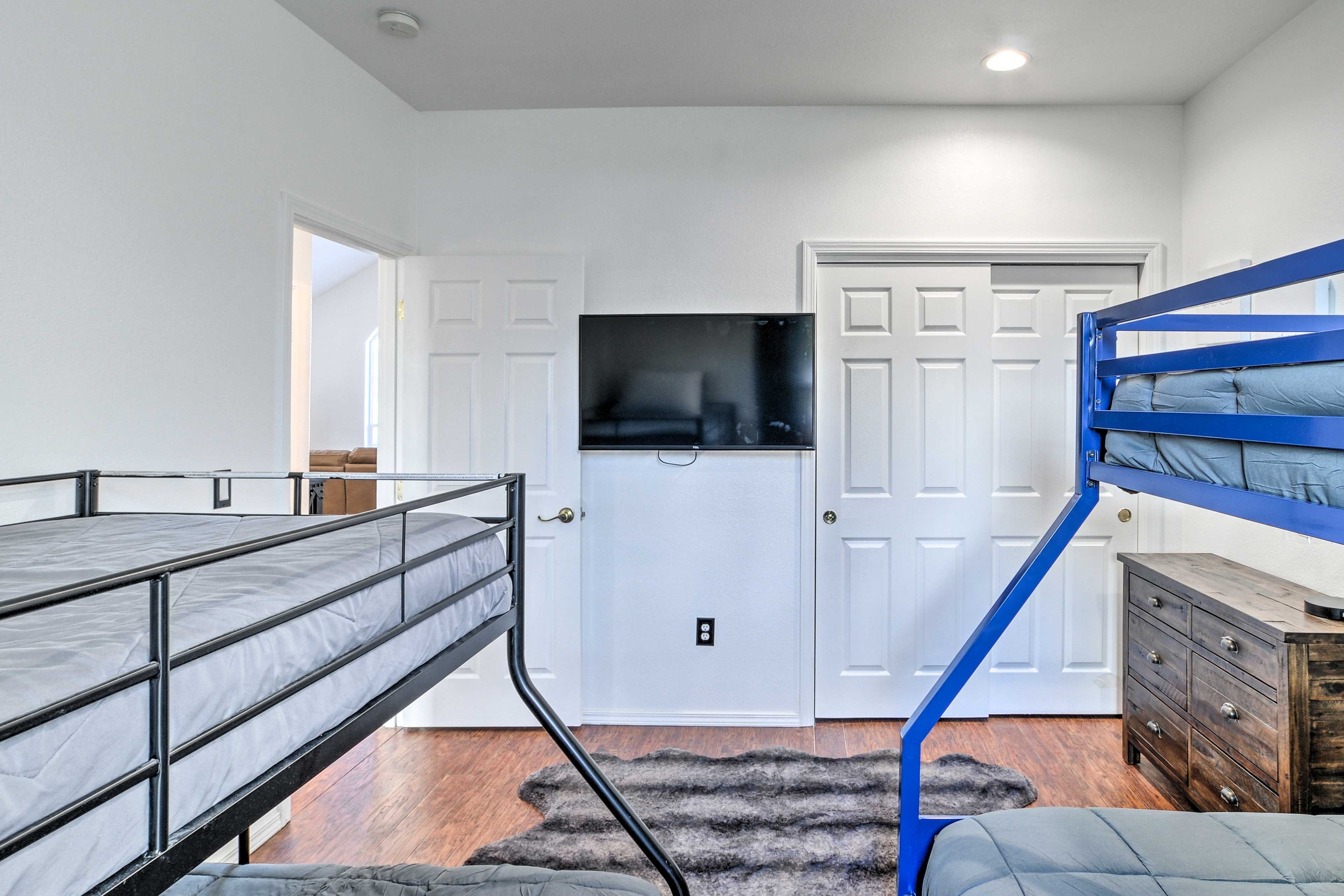 A bedroom with bunk beds, a dresser, and a television on the wall.