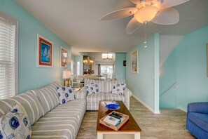A living room with a striped sofa, a wooden coffee table, and a ceiling fan.