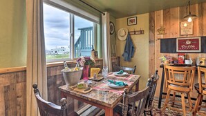 A dining area with a table set for two, wooden chairs, a view through a window, and a rustic decor. - Flathead Lake-view Studio: 38 Mi to Blacktail (Big Arm)