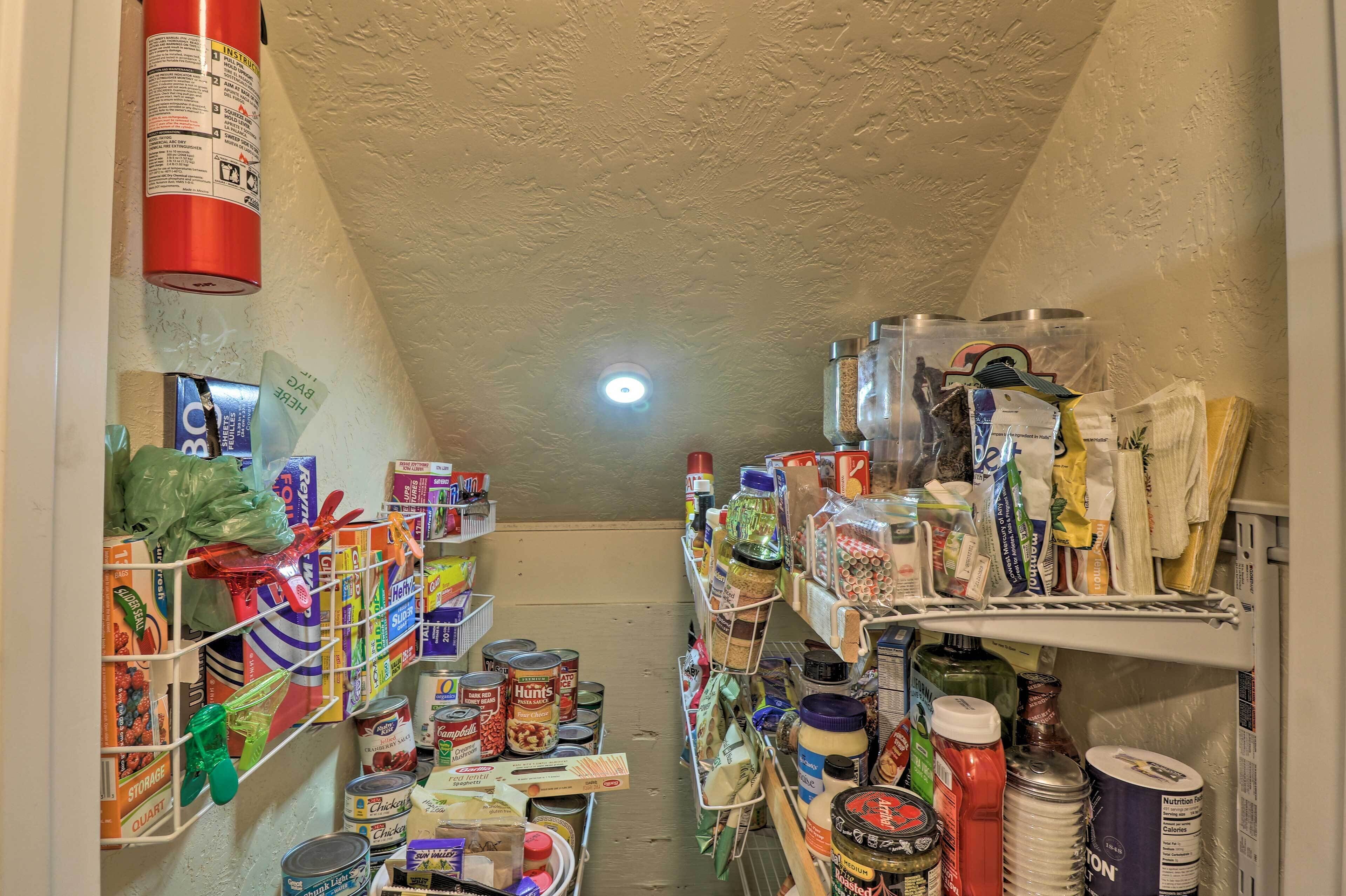 A narrow, cluttered pantry with shelves stocked with canned goods, jars, and various food items.