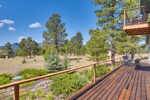 A wooden deck with outdoor furniture, overlooking a forested area with pine trees and a mountain in the distance. - Spacious Mountain Home, 10 Mi to Angel Fire Resort (Angel Fire)