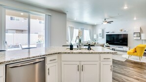 A modern kitchen with white cabinets, a stainless steel dishwasher, and a granite countertop. - Fresno Home w/ Grill - 9 Mi to Downtown (Fresno)
