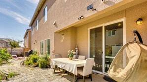 A patio with a table and chairs, a hanging chair, and a glass door leading to a covered area. - Fresno Home w/ Grill - 9 Mi to Downtown (Fresno)