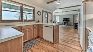 A modern kitchen with wooden cabinets, a dishwasher, and a large window. - Lake-view Retreat w/ Fire Pit in Mountain Home! (Mountain Home)