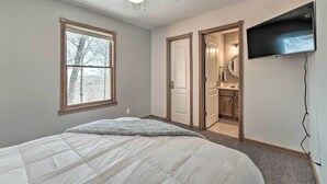 A bedroom with a bed, a ceiling fan, a TV mounted on the wall, and a window. - Lake-view Retreat w/ Fire Pit in Mountain Home! (Mountain Home)
