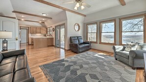 A spacious living area with a fireplace, a ceiling fan, and large windows. - Lake-view Retreat w/ Fire Pit in Mountain Home! (Mountain Home)