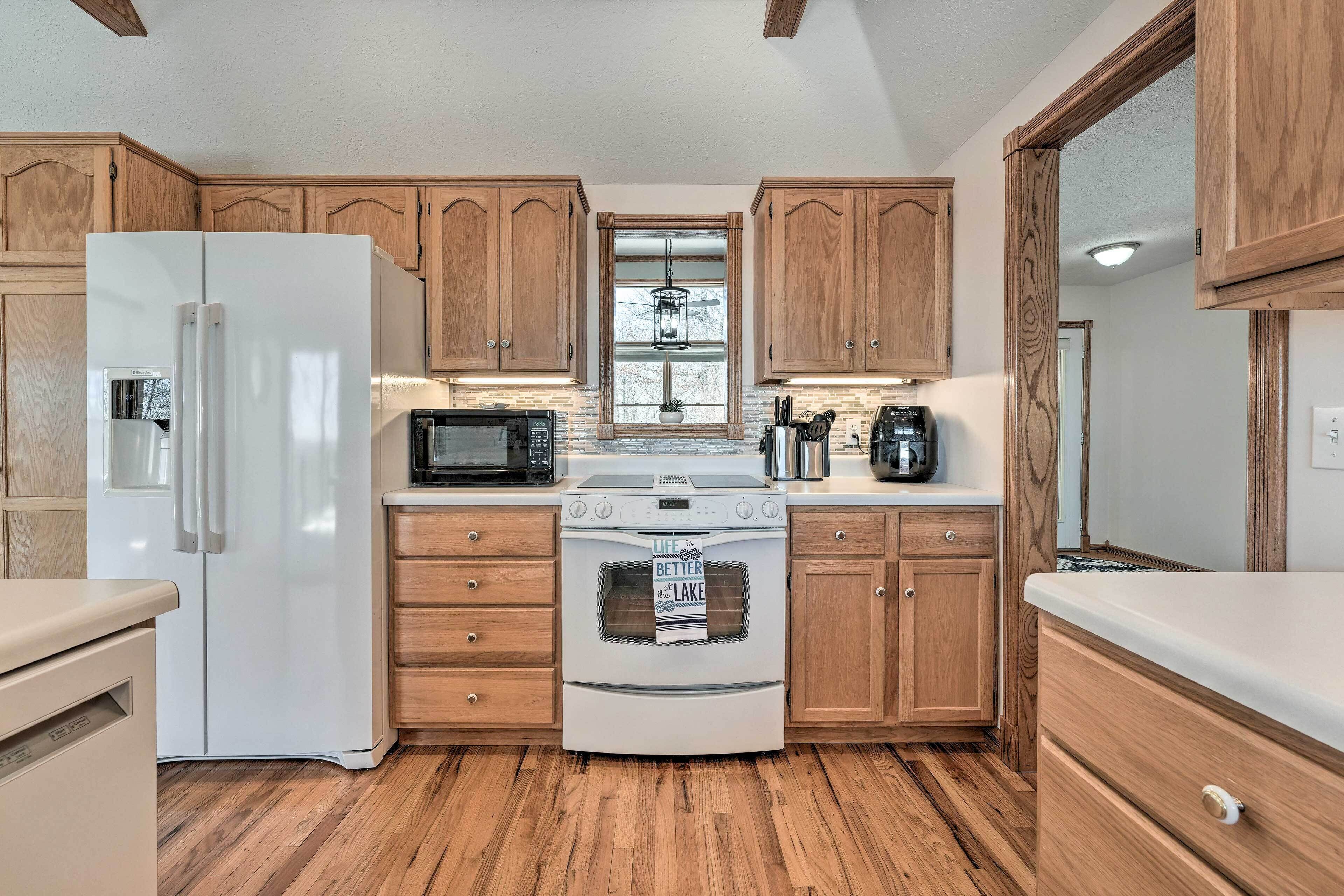 A kitchen with wooden cabinets, a white refrigerator, a microwave, a stove, and a sink.