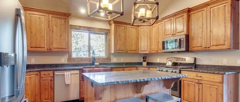 A modern kitchen with wooden cabinets, stainless steel appliances, and a central island with stools.
