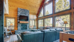 A cozy living room with a stone fireplace, leather sofa, and large windows. - 'longview Lodge' w/ Furnished Deck & Fire Pit! (Duck Creek Village)
