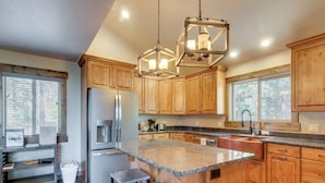 A kitchen with wooden cabinets, a granite countertop, a stainless steel refrigerator, and a pendant light fixture. - 'longview Lodge' w/ Furnished Deck & Fire Pit! (Duck Creek Village)