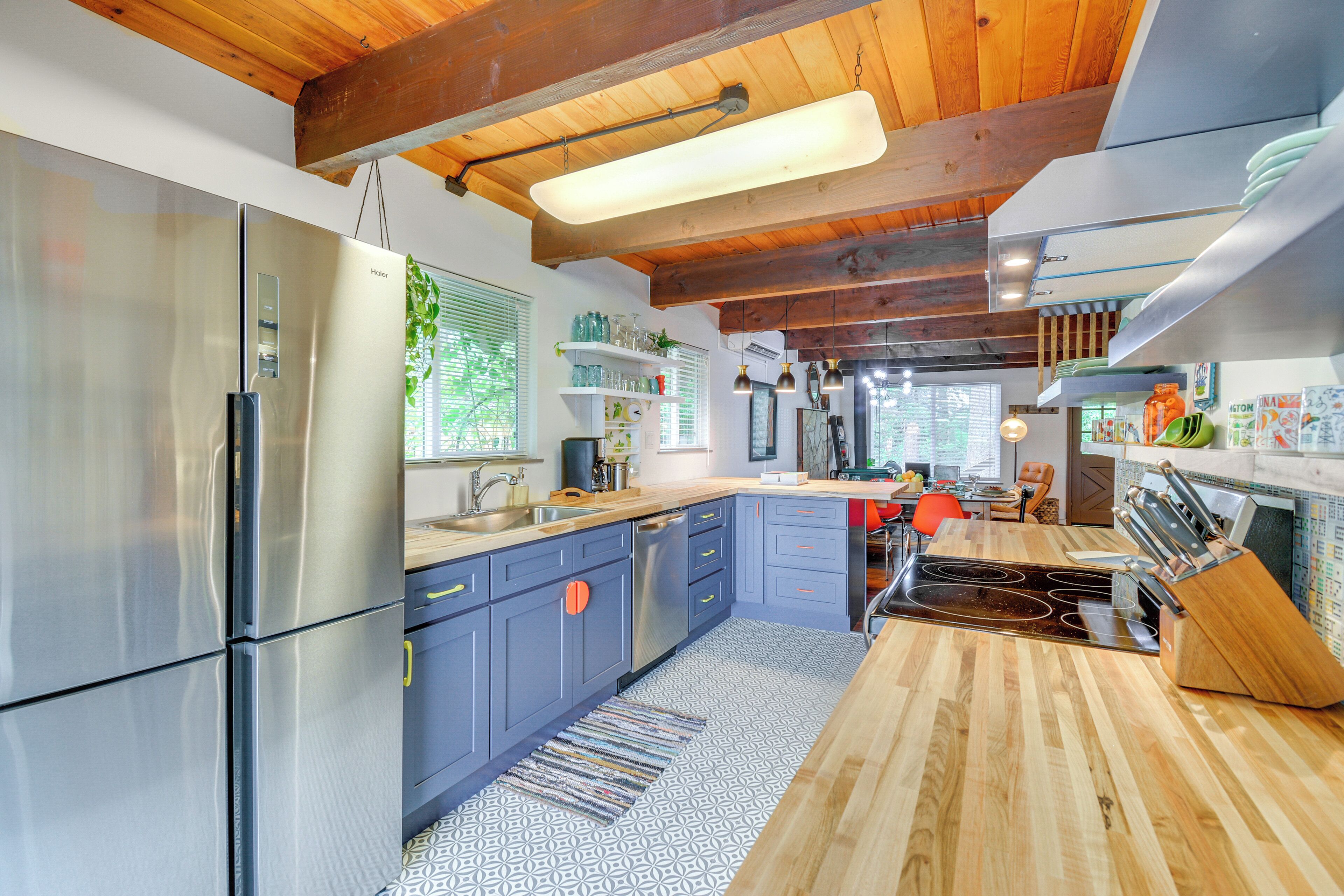 A modern kitchen with stainless steel appliances, wooden ceiling beams, and a central island with a stove.