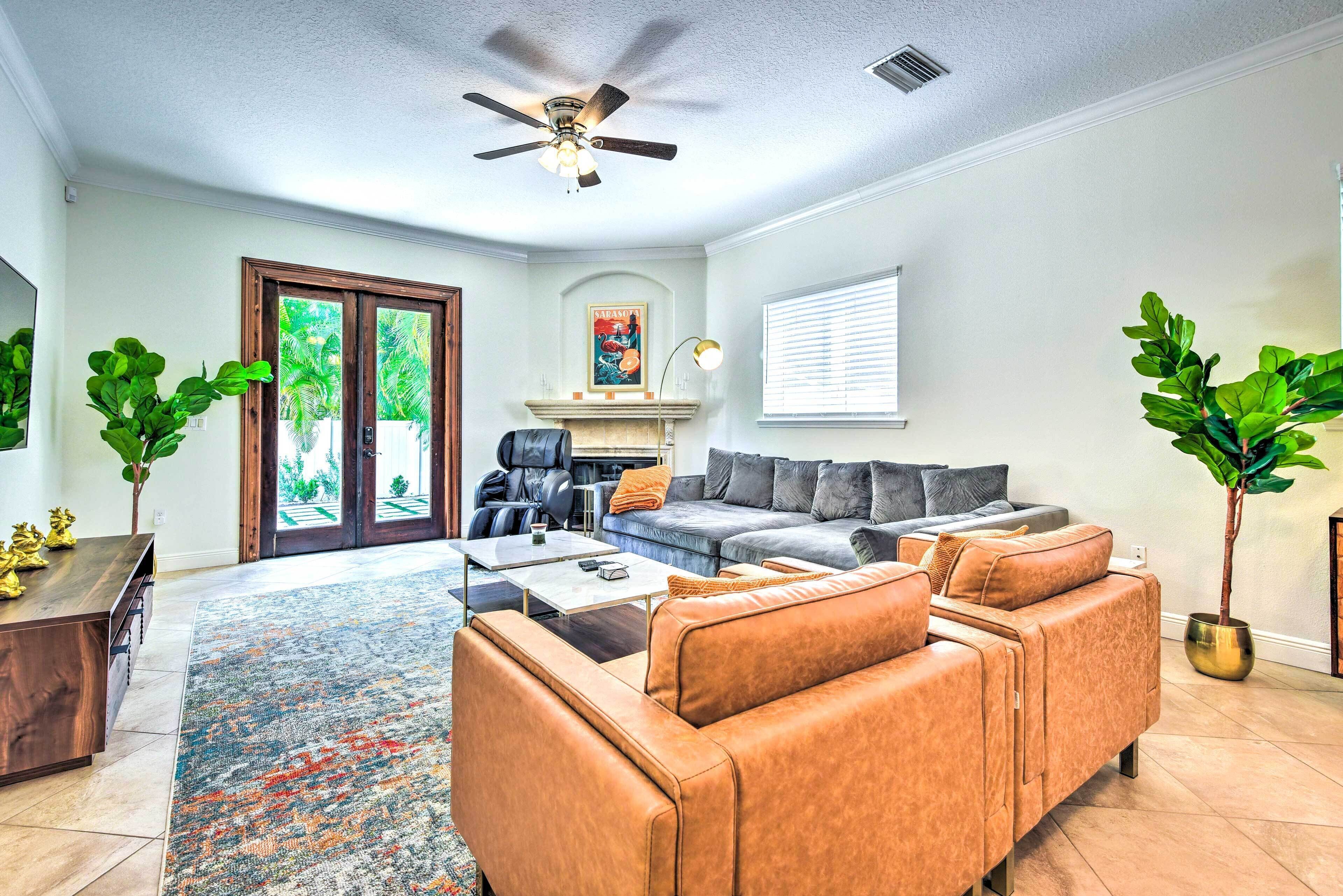 A living room with a sofa, coffee table, and chairs, a fireplace, and a ceiling fan.