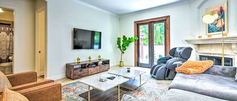 Una sala de estar con sofá, sillones, una mesa de centro, televisor, chimenea y un ventanal grande.