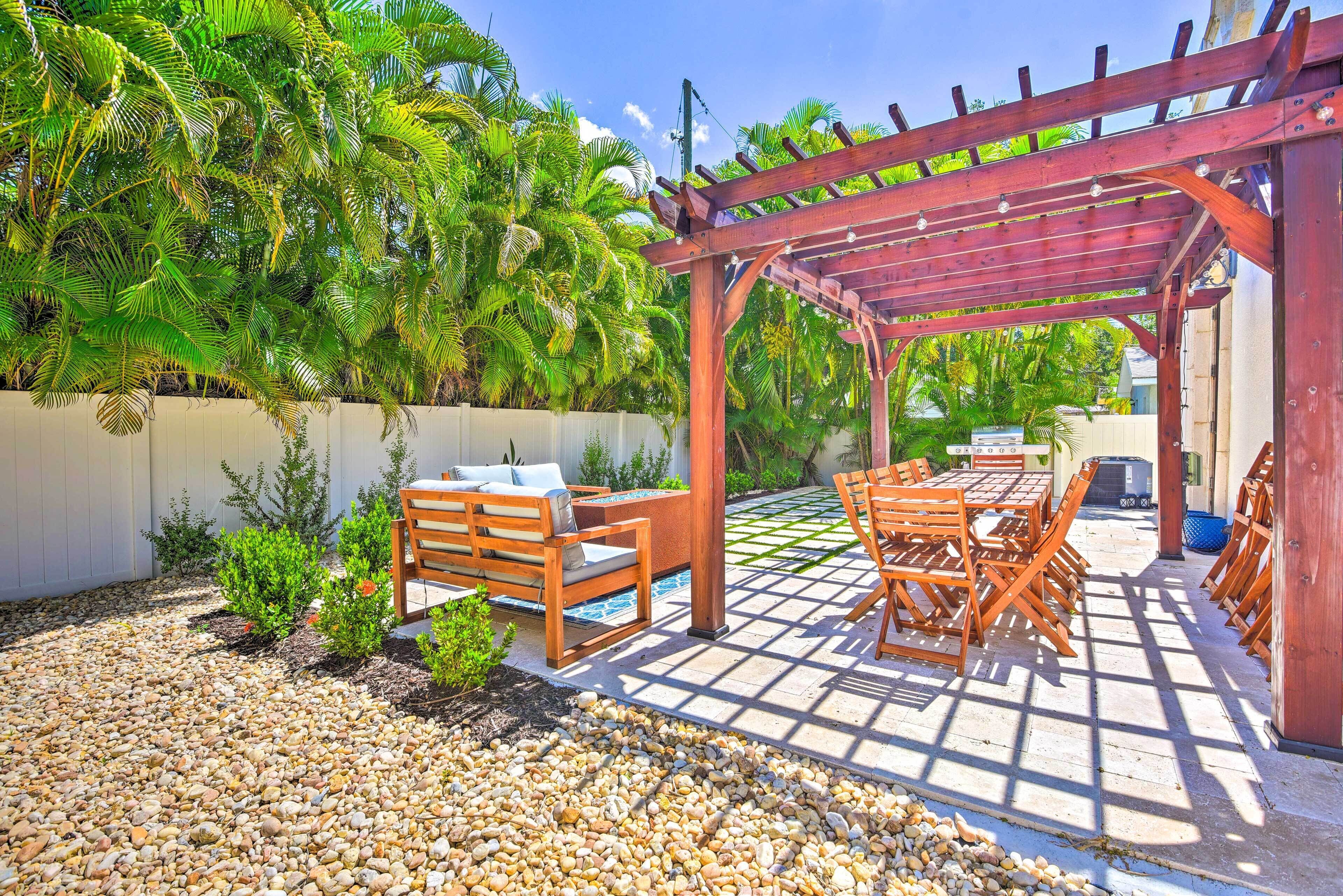 A patio area with a pergola, outdoor furniture, and a tiled floor.