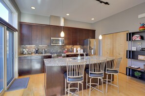 A modern kitchen with dark wood cabinets, stainless steel appliances, and a central island with bar stools. - Downtown Condo w/ Rooftop Patio & City Views! (Omaha)