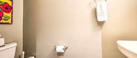 Une salle de bain équipée de toilettes, d’un porte-serviettes et d’un support à papier toilette.