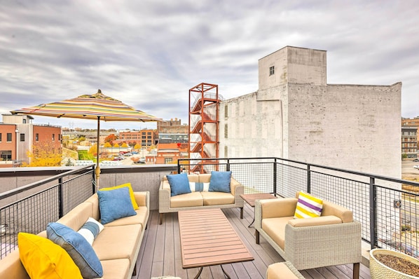 A rooftop terrace with outdoor seating, a fire escape, and a view of the cityscape. - Downtown Condo w/ Rooftop Patio & City Views! (Omaha)
