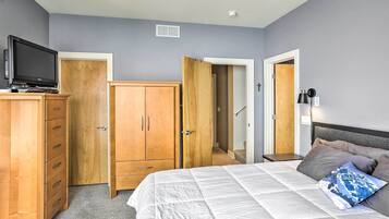 A bedroom with a bed, wooden wardrobe, and a television on a stand.