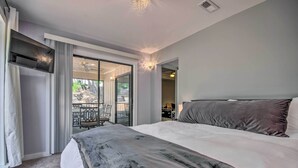 A modern hotel room with a large bed, a flat-screen TV, a ceiling fan, and a balcony with outdoor furniture. - 1 Mi to Lake of the Ozarks: Condo w/ Pool Access (Lake Ozark)