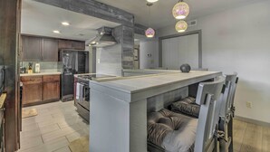 A modern kitchen with dark wood cabinets, a central island, and pendant lighting. - 1 Mi to Lake of the Ozarks: Condo w/ Pool Access (Lake Ozark)