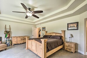 Un dormitorio con una cama de madera, una mesita de noche, un aparador, un ventilador de techo y un cuadro enmarcado en la pared.