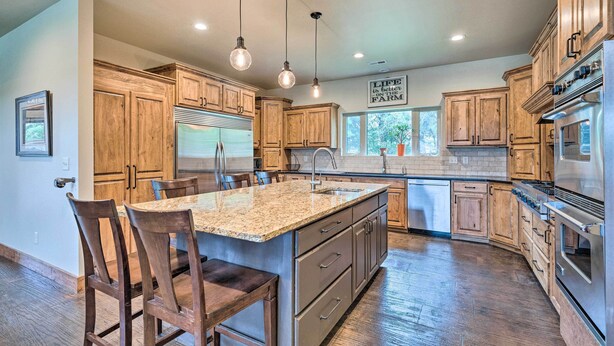 A kitchen with wooden cabinets, a granite countertop island, and stainless steel appliances.
