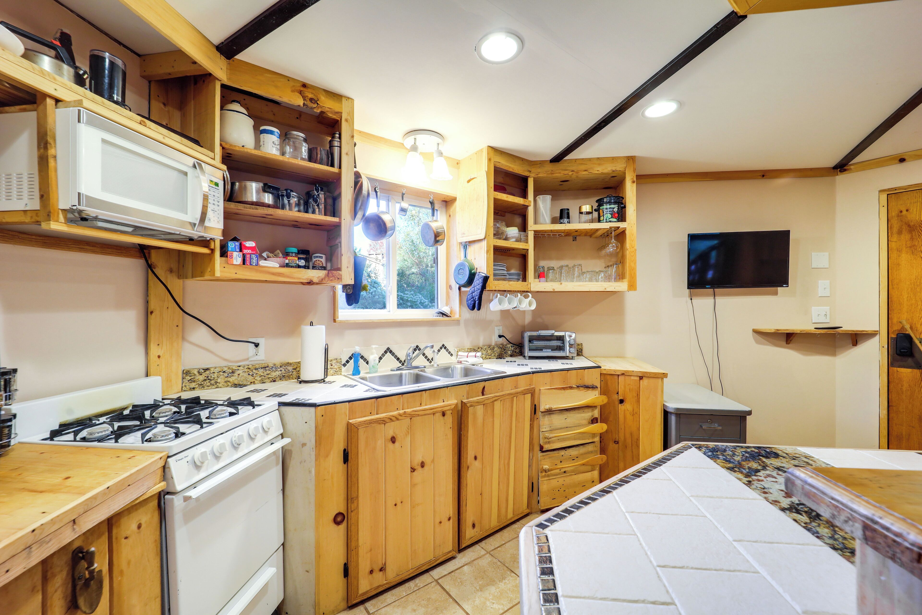 A kitchen with wooden cabinets, a stove, a microwave, and a window.