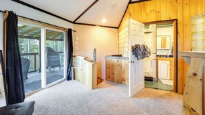 A cozy cabin interior with a large sliding glass door leading to a deck, a compact kitchenette, and a small bathroom. - Unique West Jefferson Home w/ Fire Pit & Grill! (West Jefferson)