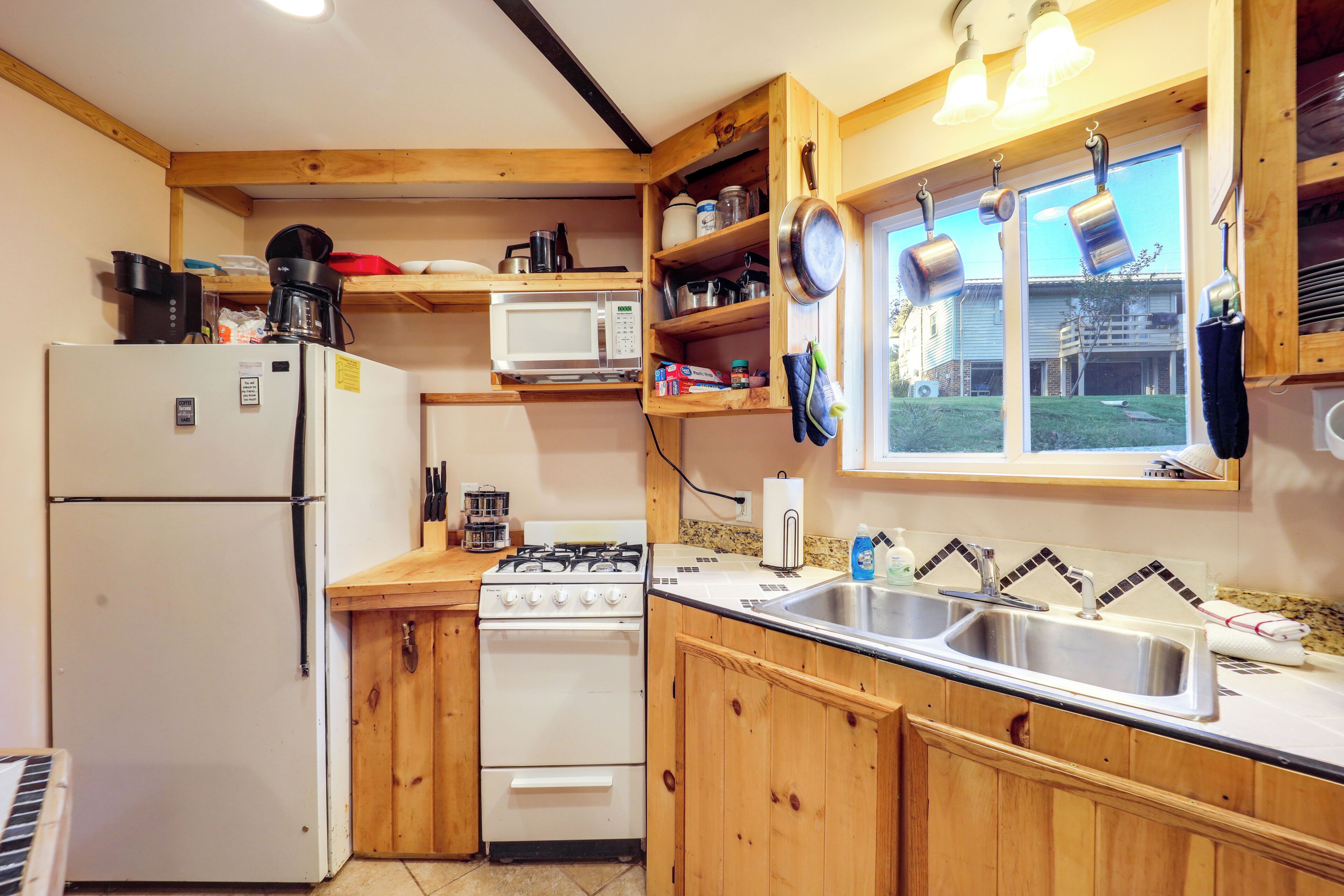 A compact kitchen with a refrigerator, stove, microwave, and wooden cabinets.