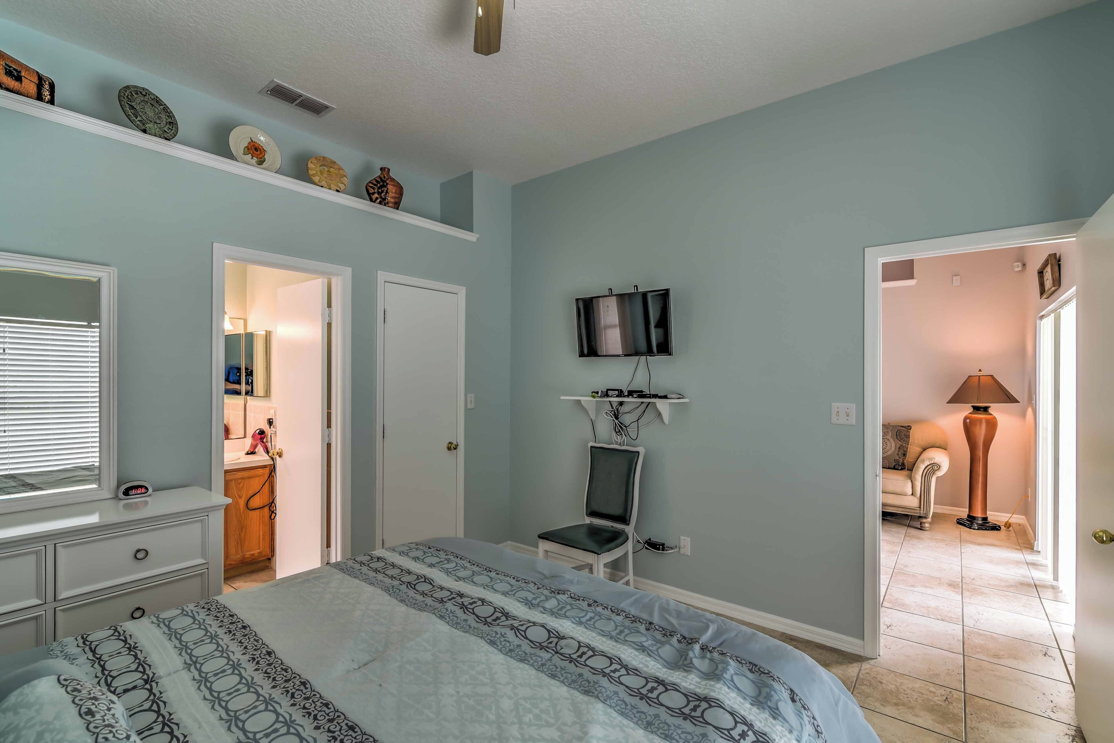 A bedroom with a bed, a dresser, a TV on a shelf, and a chair.