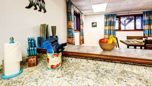 A kitchen with a marble countertop, a bear decoration on the wall, and a window with curtains. - Ideally Located Fairbanks Vacation Rental! (Fairbanks)