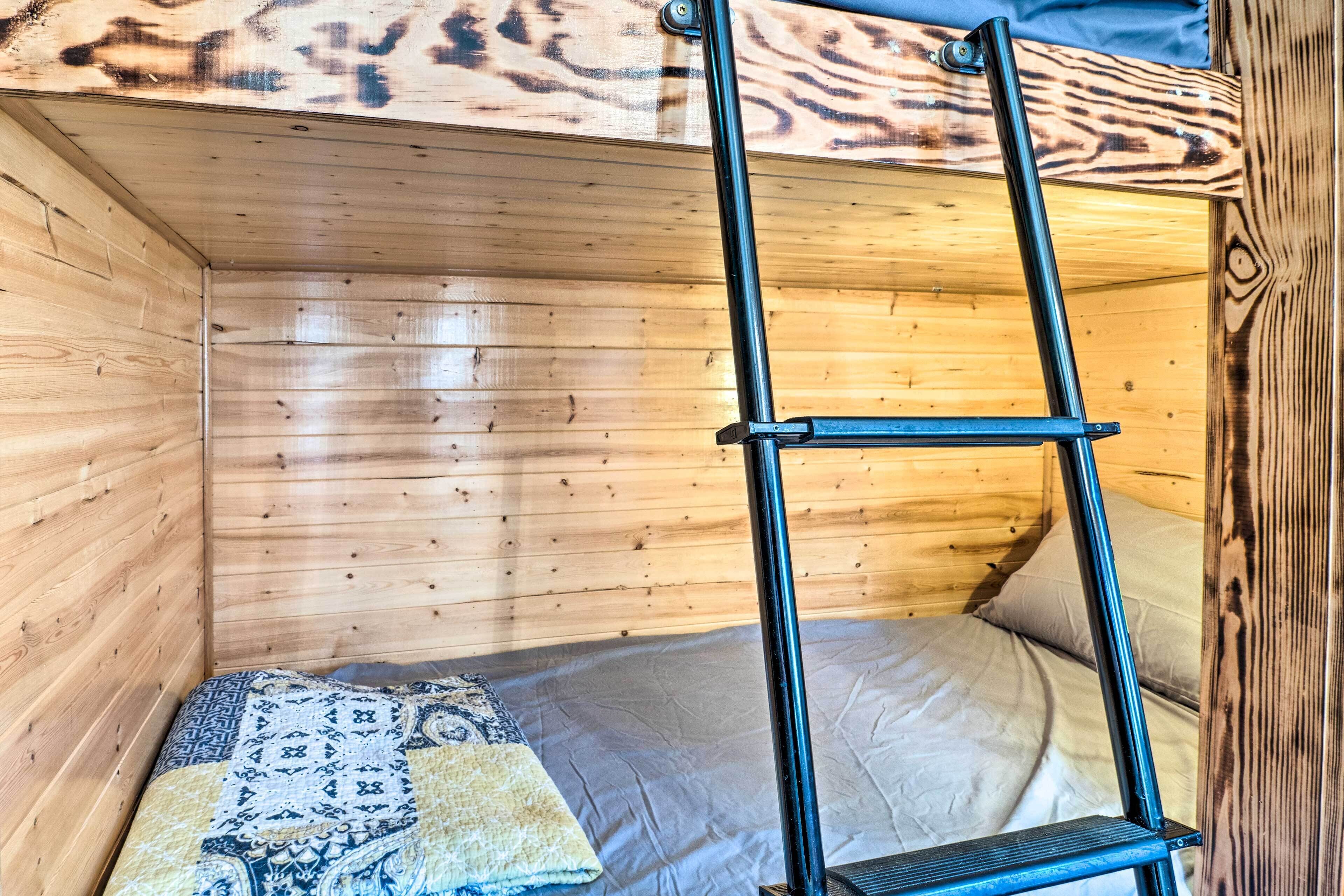Una habitación de cabaña de madera con una litera, una escalera y una colcha estampada.